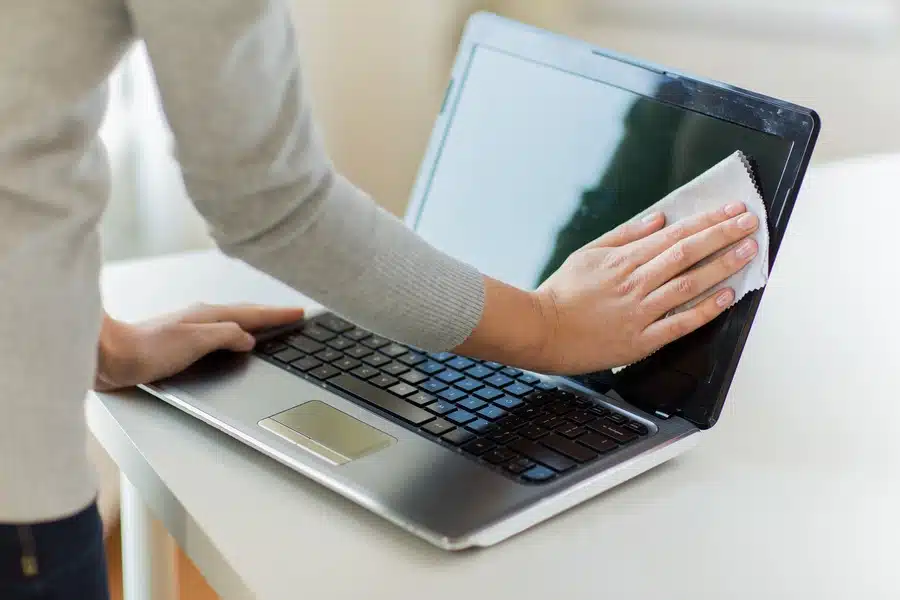 Man cleaning the screen of his computer.