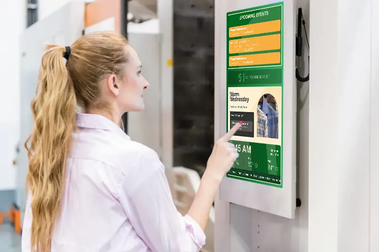 Manufacturer employee checking out some information through digital signage.
