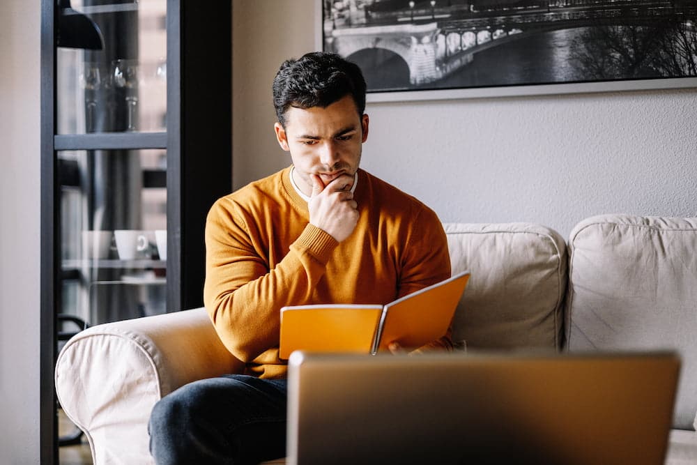 Young man sitting on sofa thinking about the digital signage project.