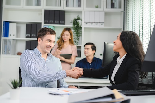 two employees shaking hands together and enhancing engagement in the office