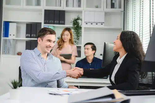 two employees shaking hands together and enhancing engagement in the office