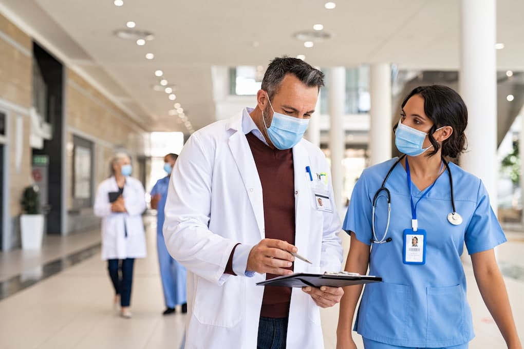 shift workers at a hospital: nurse and doctor communicating about patient's reords