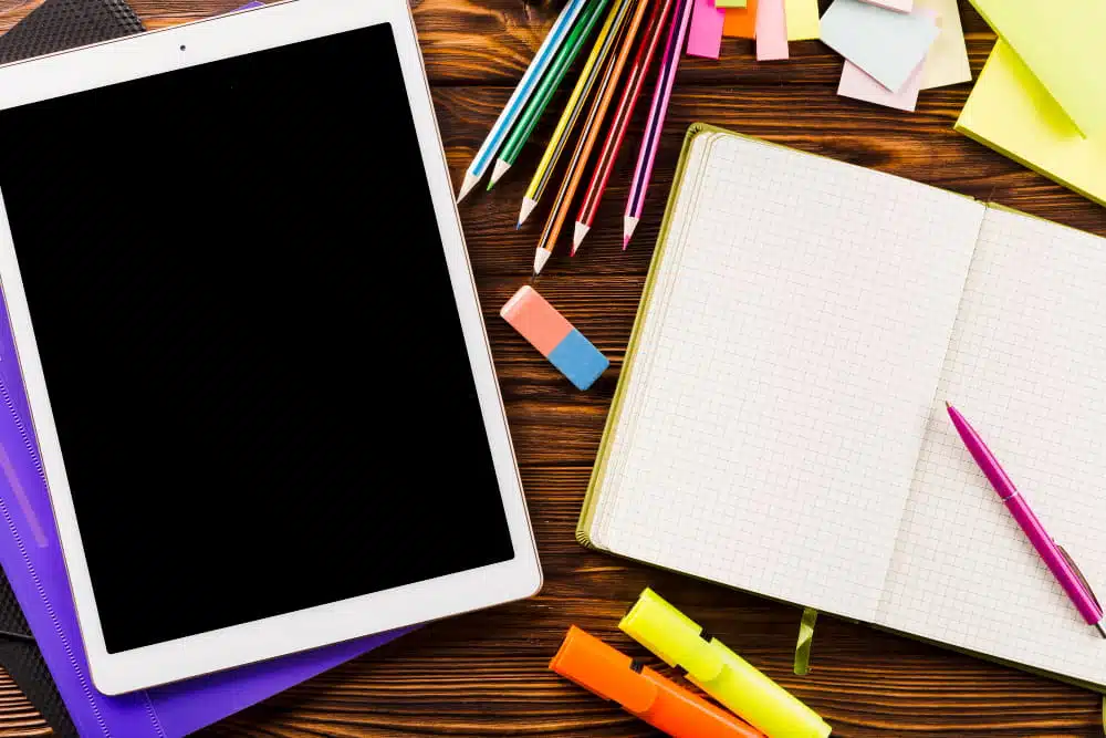 ipad and notebooks and other school materials on a table